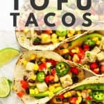 Row of tofu tacos with lime wedges.