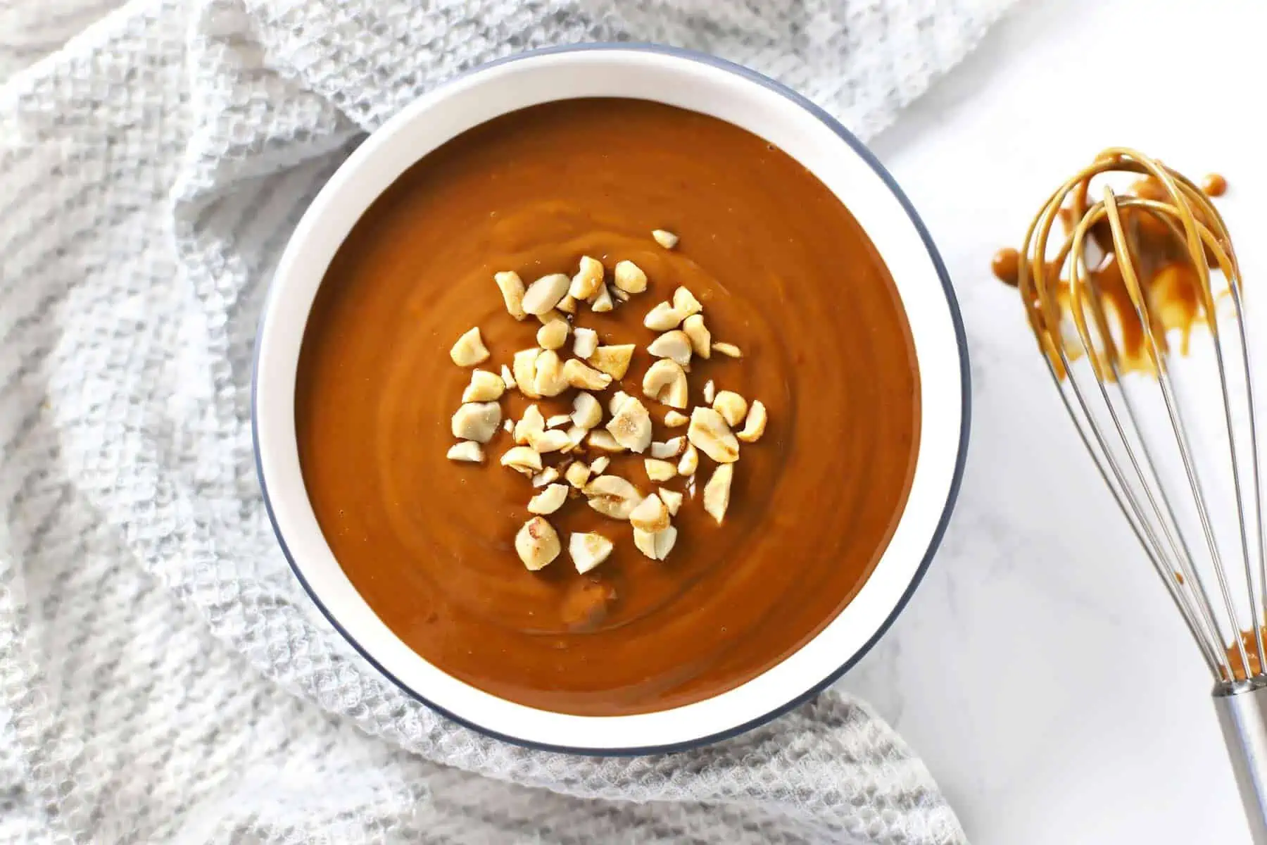 Easy spicy peanut sauce in round dish with whisk.