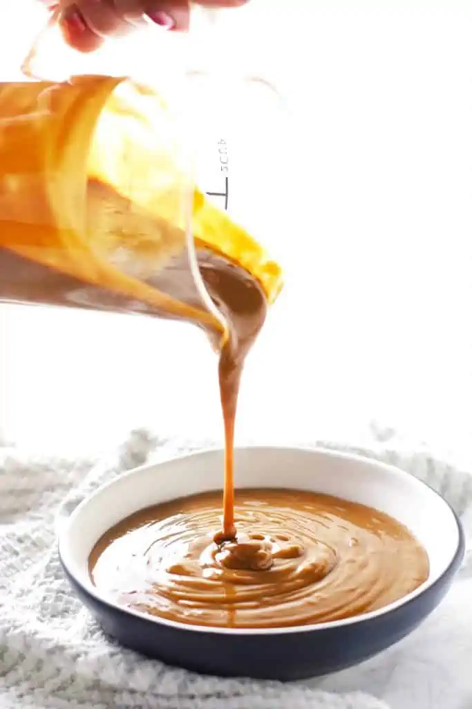 Peanut sauce being poured into bowl. 