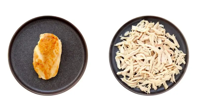 Chicken breast on plate next to plate of shredded chicken.