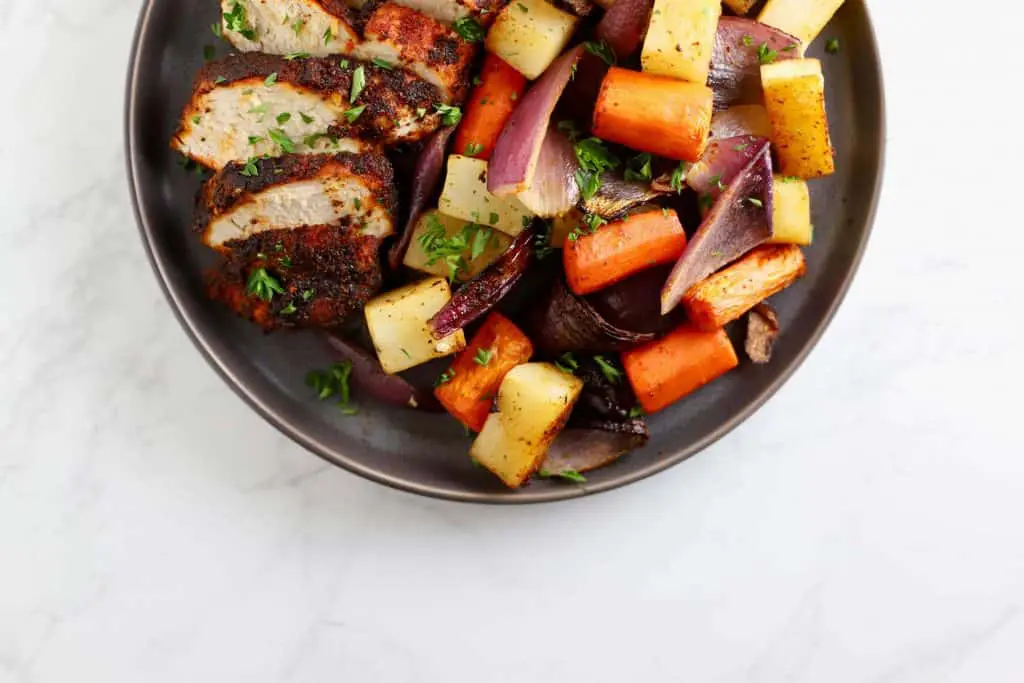 Chicken and vegetables on grey plate.