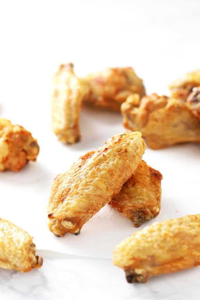 Crispy air fryer chicken wings on white surface.