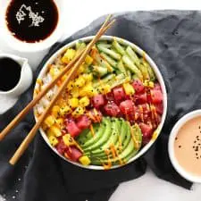 Tuna poke sushi bowl on grey napkin with chopsticks.