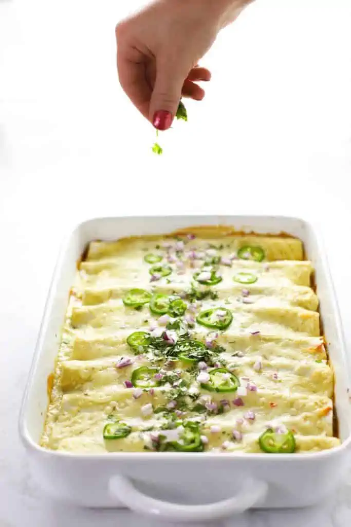 Vegetarian black bean enchiladas in a white dish. 