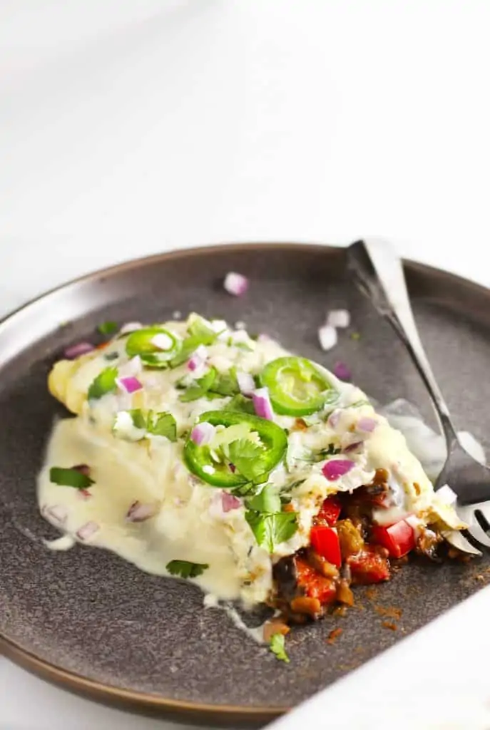 Vegetarian black bean enchiladas on a grey plate.