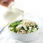 Creamy lemon garlic cashew sauce being poured on salad.