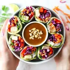 Crispy tofu summer rolls in white bowl with peanut sauce.