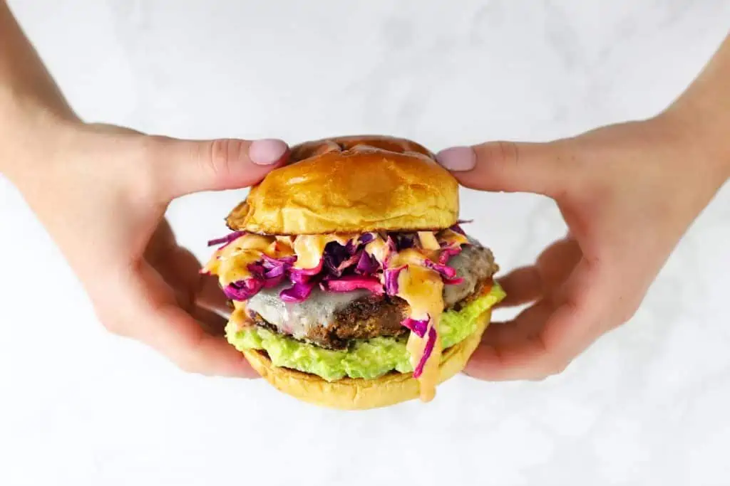 Two hands holding a black bean veggie burger.