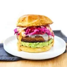 Black bean veggie burger on white plate with blue napkin.