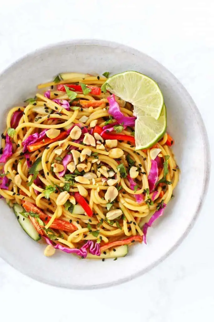 Thai noodle salad with peanut dressing in grey bowl with limes. 