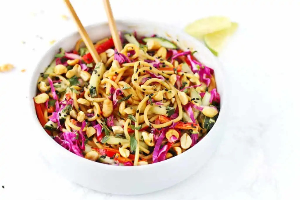 Thai noodle salad with peanut sauce in white bowl with chopsticks.