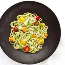 Creamy basil cashew pasta in black bowl.