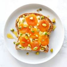 Dried apricot and mascarpone toast on white plate.