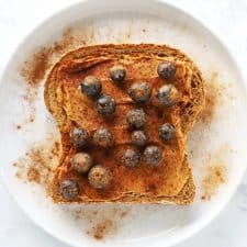 Peanut butter blueberry toast on white plate with cinnamon.