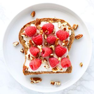 Raspberry cream cheese toast with pecans on white plate.
