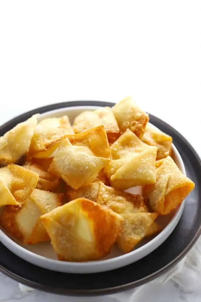 Cream cheese wontons on gray plate. 