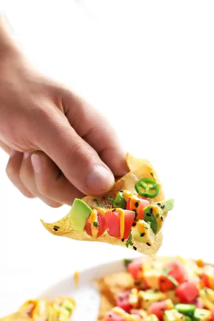 Hand holding a spicy ahi tuna wonton nacho.