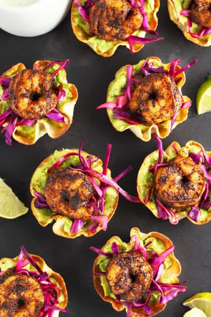 Wonton cups with spiced shrimp and lime wedges.