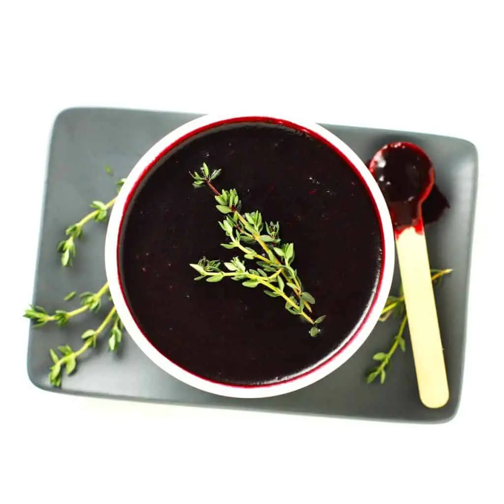 Blueberry lemon thyme sauce in white bowl one grey plate.