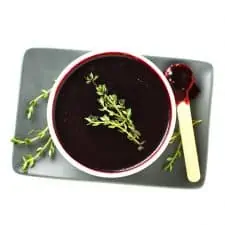 Blueberry lemon thyme sauce in white bowl with wood spoon.