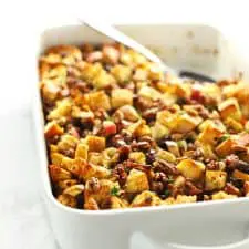 Stuffing in white casserole dish with serving spoon.