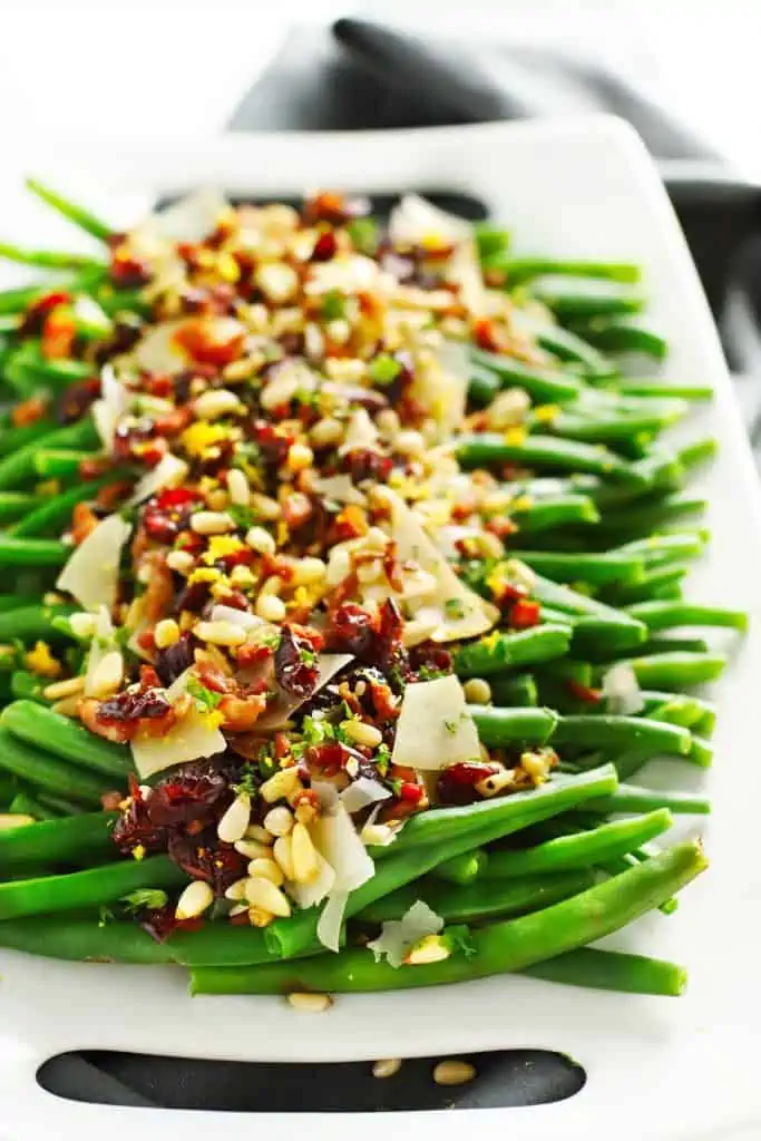 Lemon garlic green beans loaded with toppings on white tray. 