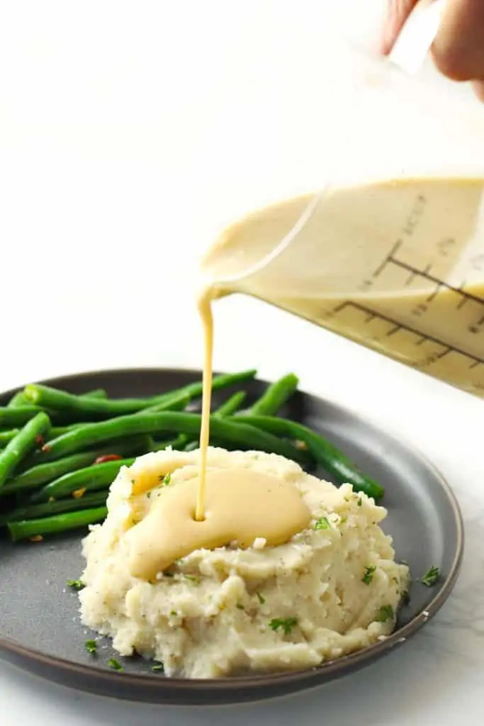 Pouring gravy on mashed potatoes.