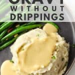 Mashed potatoes and gravy on grey plate with green beans.
