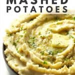 Mashed potatoes in grey dish topped with parsley and a slice of butter.