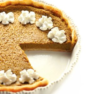 Pumpkin pie in white dish with whipped cream.