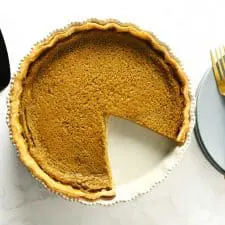 Easy pumpkin pie next to serving spatula, plates and forks.