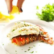 Squeezing lemon on baked lobster tail.