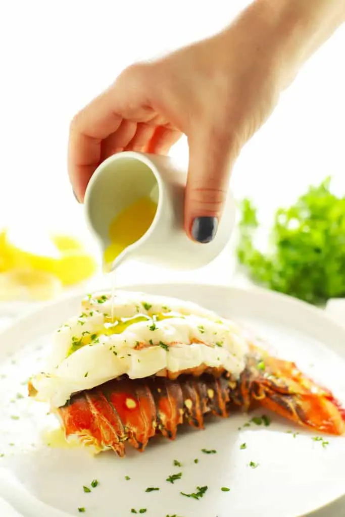 Pouring butter on baked lobster tail. 