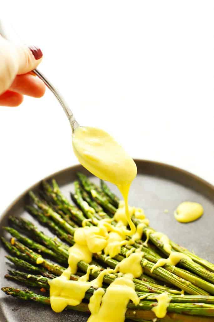 Spooning hollandaise sauce onto asparagus. 