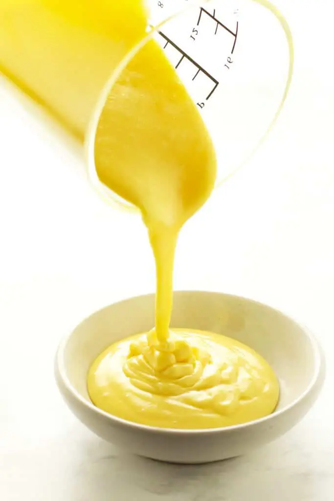 Pouring blender hollandaise sauce into white dish. 