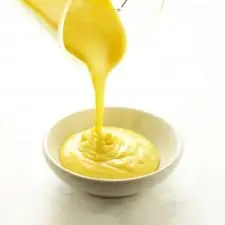 Pouring blending hollandaise into white dish.