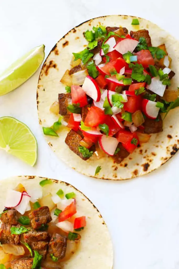 Authentic Mexican street tacos with lime wedges. 