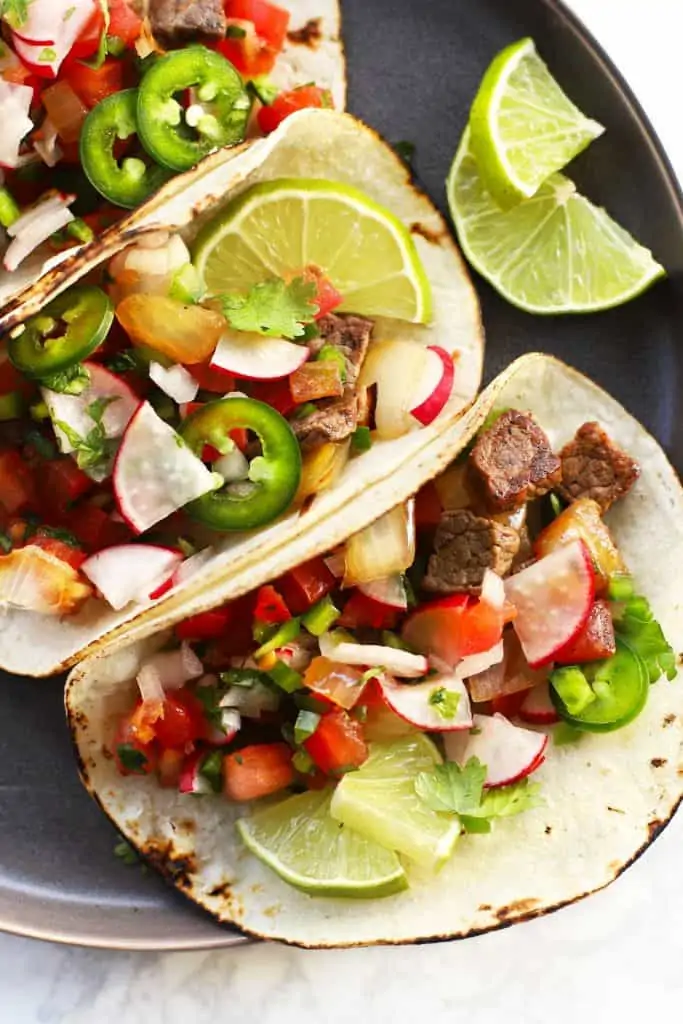 Mexican street tacos on grey plate.