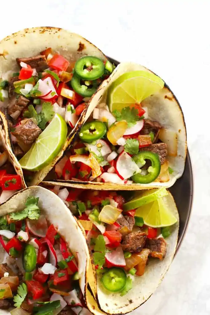 Mexican street tacos with lime wedges.