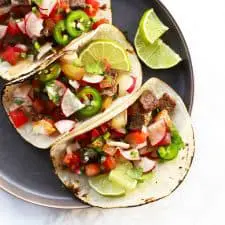 Street tacos on grey plate.