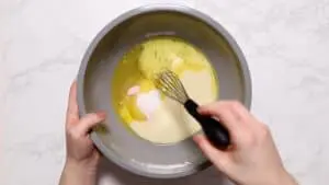 Whisking caramel ingredients in grey bowl.