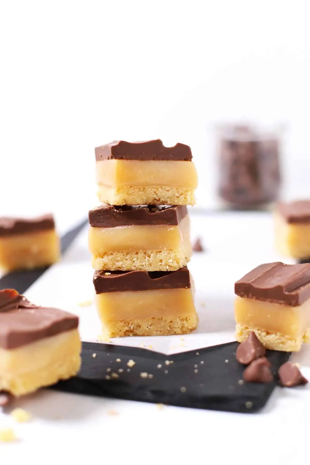 Stack of chocolate caramel cookie bars on stone cutting board. 