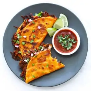 Two crispy Birria Tacos on a grey plate.