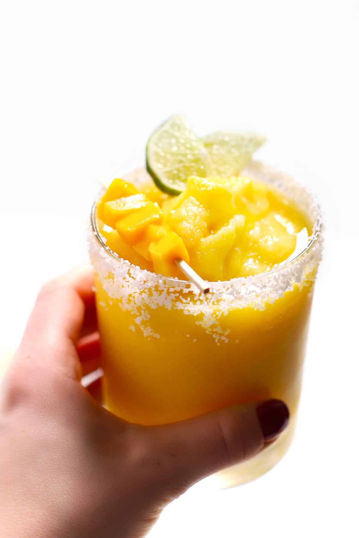 A frozen mango margarita garnished with salt, lime and mango. 