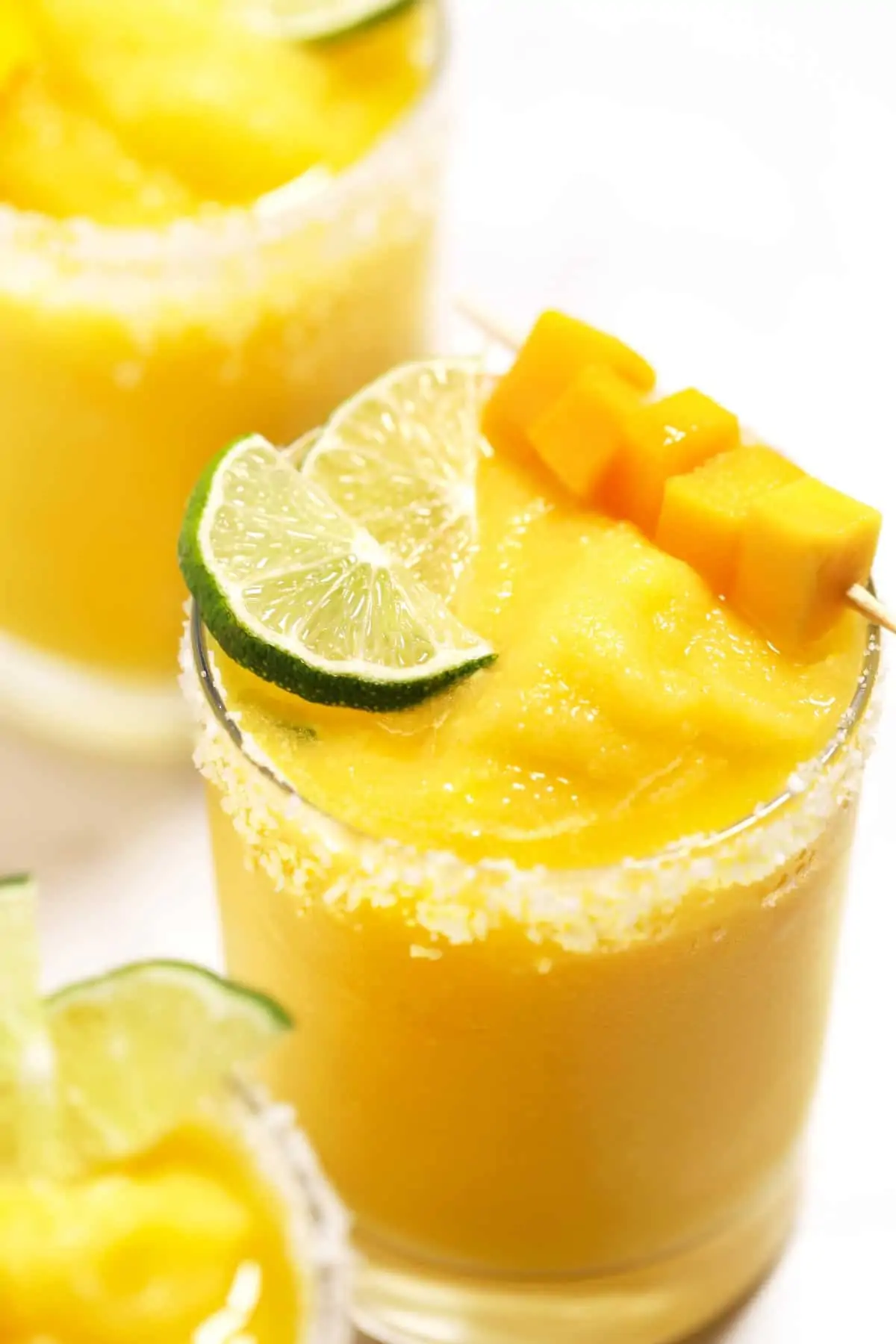 Mango margaritas garnished with lime, salt, and fresh mango. 