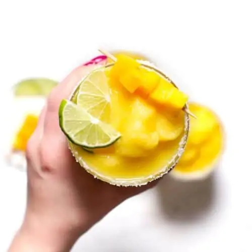 A hand holding a frozen mango margarita.