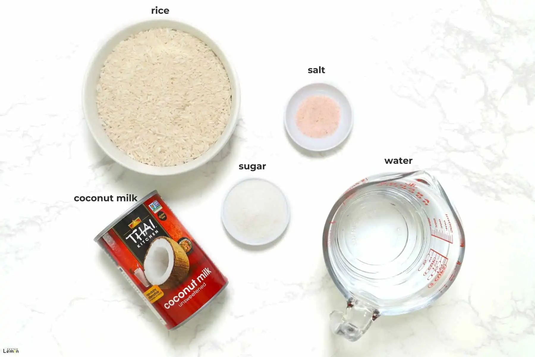 Ingredients needed to make coconut rice on a marble surface. 