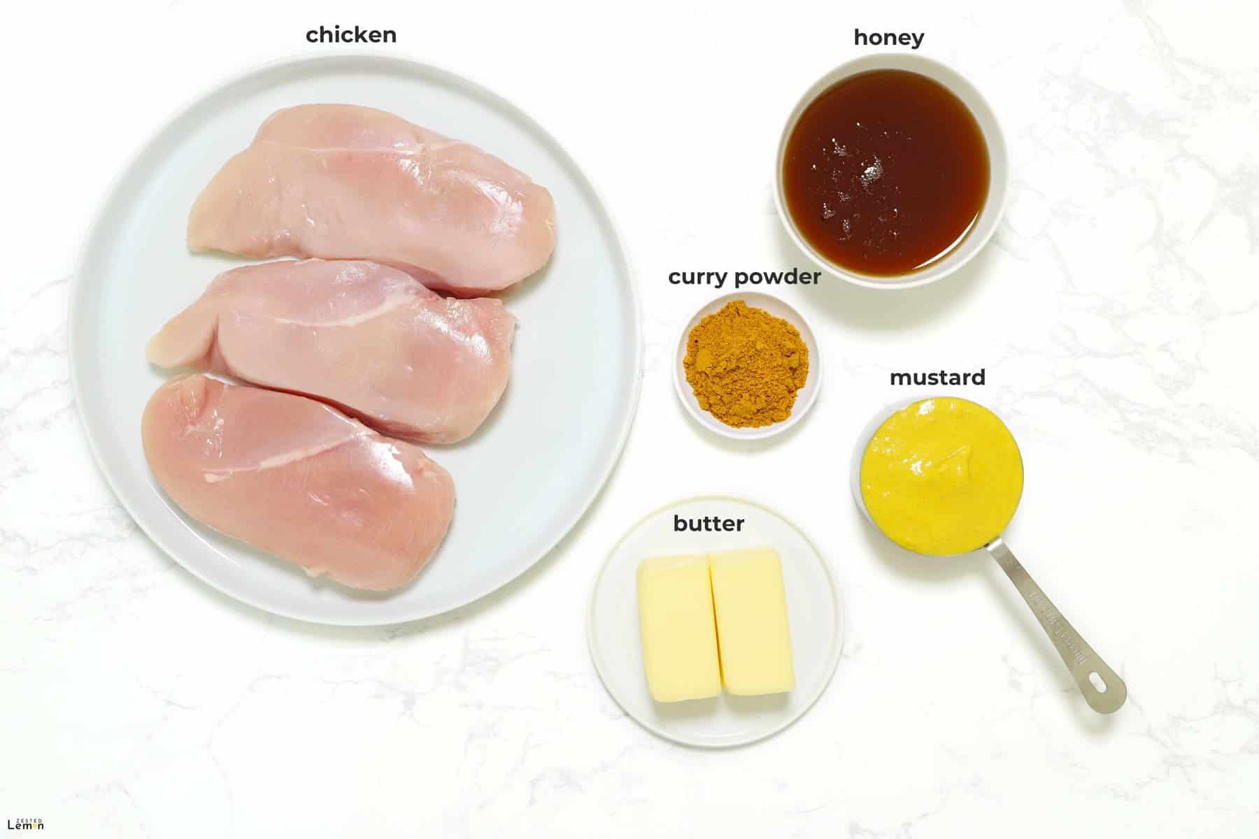 Ingredients needed to make Honey Curry Chicken on a marble surface. 