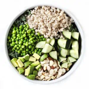 A green grain salad in a round white bowl