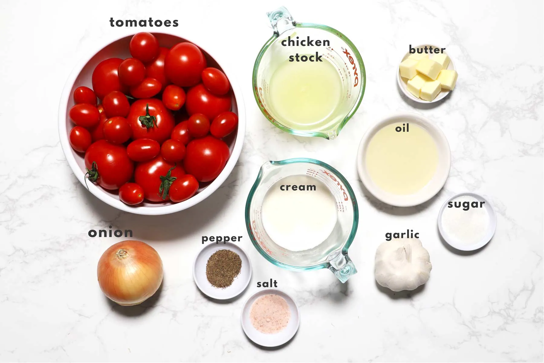 Ingredients for tomato soup on a marble surface. 